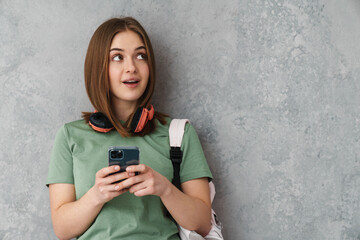 Thinking nice girl with headphones using cellphone and looking upward
