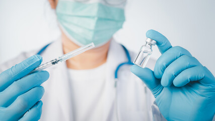 Doctor wear hand in blue gloves holding a syringe with liquid vaccines,Concept covid-19 corona virus.