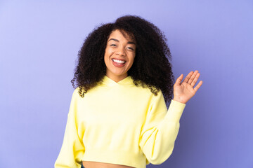 Young african american woman isolated on purple background saluting with hand with happy expression