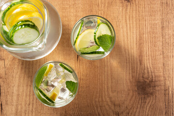 Sassy water or water with cucumber and lemon on wooden table. Top view	