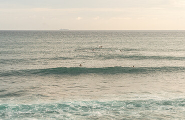 Surfer pośr&oacute;d fal na oceanie na tle zachodu słońca.