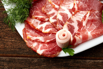 Dish with prosciutto, capicola and Parma ham, herbs. Close-up