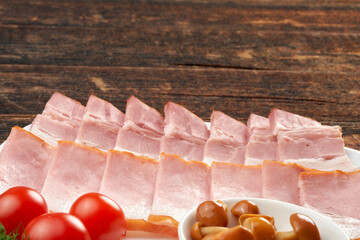 Ham on a plate, still life on a wooden natural background.