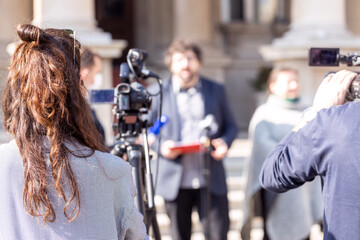 Female camerawoman shooting media event or news conference with a video camera. Public relations - PR concept.