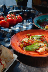 Baked fish in an orange clay plate with lemon and olives at the buffet