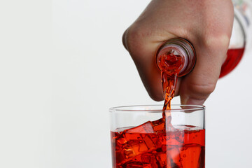 Man pouring orange drink into glass with ice closeup. Nonalcoholic cocktails concept