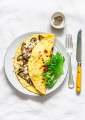 Omelet with shiitake and eringi mushrooms - delicious, healthy, vegetarian brunch on a light background, top view