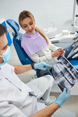 Woman peeking into the x-ray film of teeth