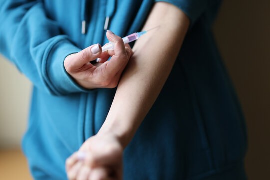 Woman making herself intravenous drug injection closeup. Heroin addiction concept