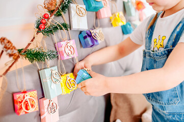 Close up of little girl hands holding present box handmade advent calendar at home. DIY xmas advent calendar for kids. Christmas, zero waste, upcycling, plastic free holidays