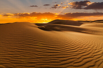 Sunset over the sand dunes in the desert. Arid landscape of the Sahara desert