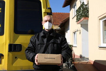Paketbote mit FFP2 Maske und Fahrzeug - Corona, Pandemie, Covid