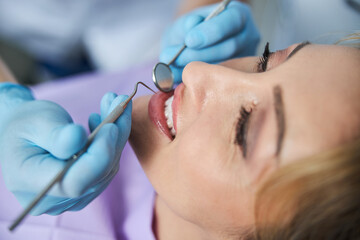 Dental specialist examining teeth with stomatological instruments