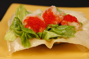 fried shrimp with flying fish roe on lettuce leaves