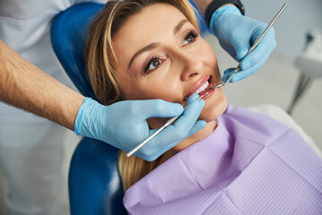 Dentist touching patient teeth with stomatological tools