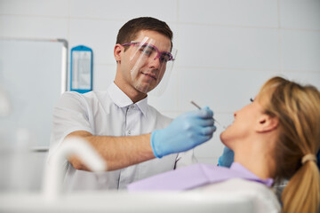 Obraz premium Collected dental professional using mouth mirror on lady