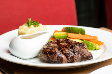 grilled beef steaks with spices with vegetables, mashed potato, and mushroom sauce.