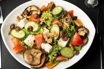 Vegetarian Salad of eggplant Halloumi, fresh tomatoes, lettuce, cucumber and nuts in top view.