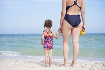 Mother daughter beach together rear view Unrecognizable caucasian woman little girl swimwear standing seaside back.
