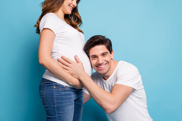 Cropped photo of optimistic couple man hug listen baby in stomach wear white t-shirts isolated on teal color background