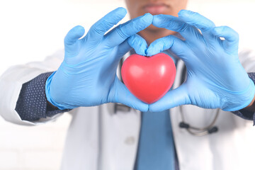  doctor hand in protective gloves holding red heart on blue 