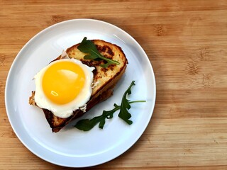 Sandwich with a fried egg, bacon, cheese and vegetables.