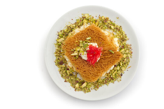 Turkish dessert kunefe, kunafa, kadayif with pistachio powder and cheese, served hot, very sweet. Turkish traditional dessert.Lebanese dessert of Kunafa isolated on white.