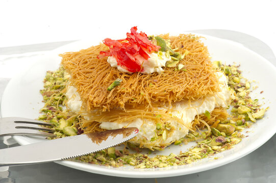 Turkish dessert kunefe, kunafa, kadayif with pistachio powder and cheese, served hot, very sweet. Turkish traditional dessert.Lebanese dessert of Kunafa isolated on white.