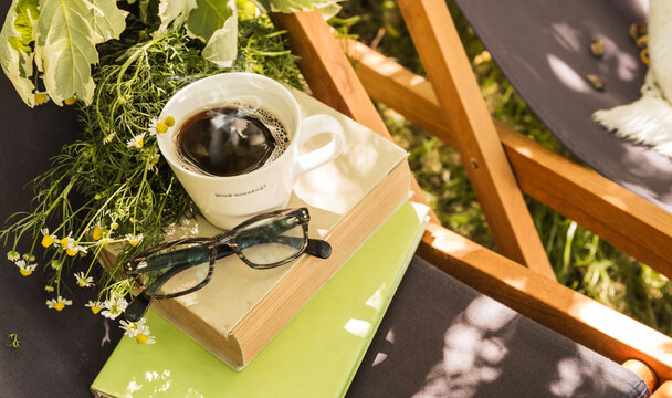Coffee and books - summer outdoor leisure in the sunny garden