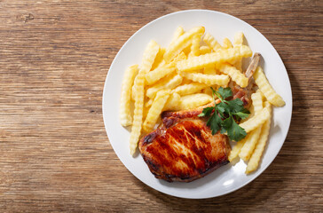 plate of grilled pork with french fries, top view