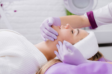 A beautician make face massage to the patient in the beauty salon