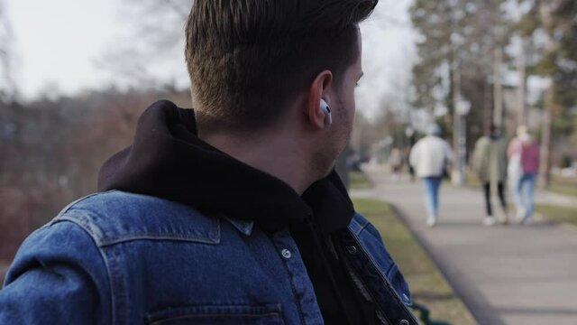 Student listeining to music in the park with airpods pros