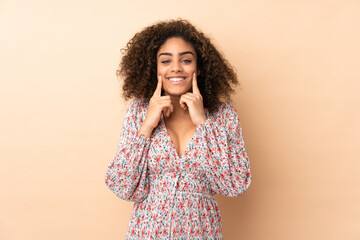 Young African American woman isolated on beige background smiling with a happy and pleasant expression