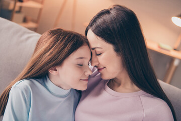 Profile photo of optimistic brunette red hairdo mom daughter hug sit on sofa wear sweater at home