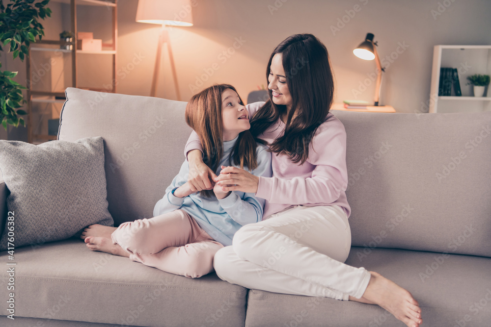 Poster Photo of optimistic brunette red hairdo mom daughter hug sit on sofa wear sweater pants at home