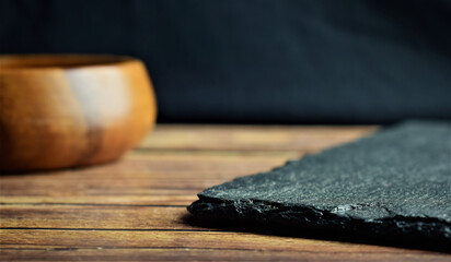 On rustic wooden boards, empty wooden bowl and rectangular slate board.