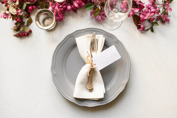 Elegance spring table setting with blooming apple flowers on white table. Top view. Festive dinner.