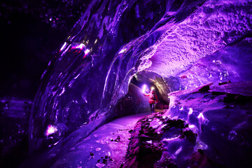 Man with pink light exploring an amazing glacial ice cave