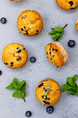 Fresh homemade delicious blueberry muffins decorated with thyme, berries and mint on grey concrete background. Top view.