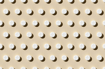 Round tablet pill pattern on a beige background. Hard shadows.