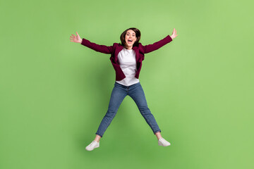 Obraz premium Full size photo of optimistic brown hairdo lady jump wear cardigan jeans sneakers isolated on green background