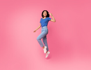 Fototapeta na wymiar Happy young asian lady jumping at studio celebrating victory