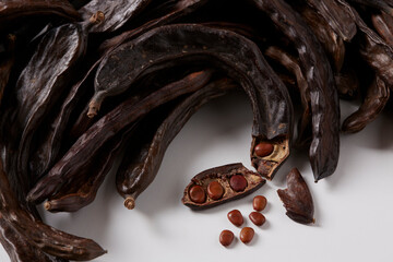 In the foreground, carob seeds and pods. All on white background. Carob from Mallorca, Spain - obrazy, fototapety, plakaty