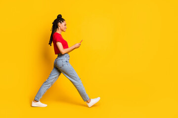 Fototapeta na wymiar Full length body size profile side view of focused cheerful girl going using gadget 5g app smm isolated bright yellow color background
