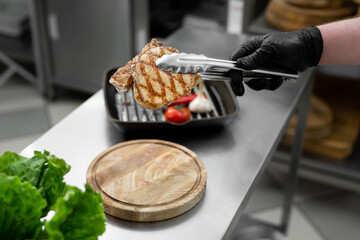 The tongs hold the cooked meat. Fried garlic and tomato