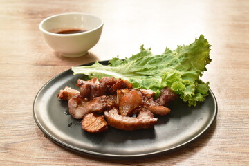 grilled pork neck and ear slice with lettuce on plate dipping spicy sauce