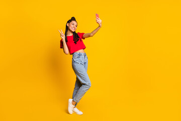 Fototapeta na wymiar Full length body size view of lovely cheerful girl making selfie posing showing v-sign having fun isolated bright yellow color background