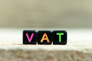 Black color block with word (Abberviation of Value added tax) on wood background