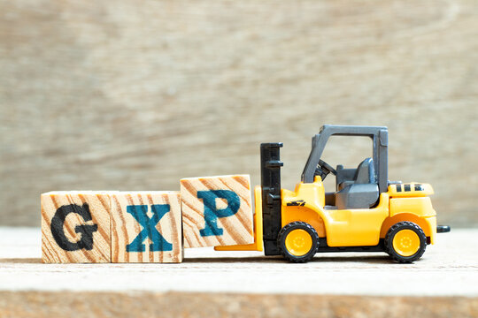 Toy forklift hold letter block P to complete word GXP on wood background