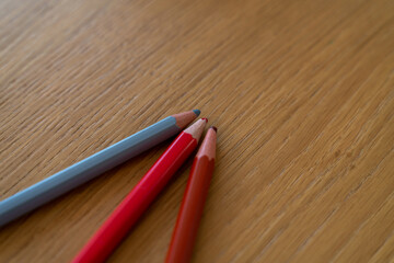 Obraz premium Trois crayons de couleur sur une table en bois clair